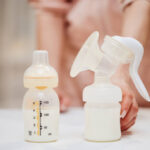 Manual Breast Pump And Bottle With Milk For Baby On Background Of Mother
